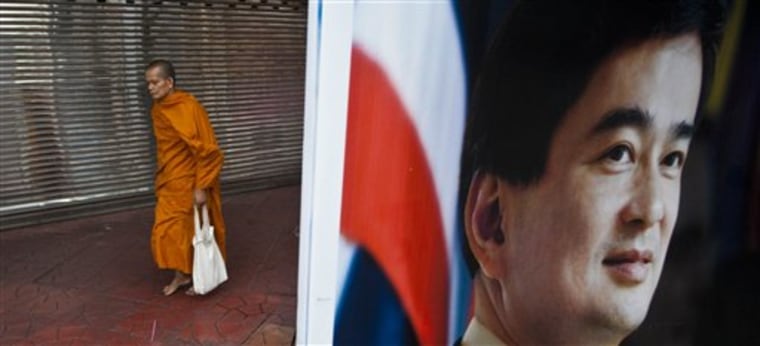 A Buddhist monk walks near an election poster for Prime Minister Abhisit Vejjajiva of Thailand's Democrat party during morning rounds in Bangkok on Sunday.